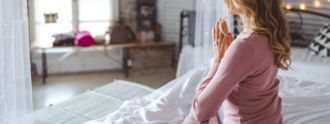 Eine Frau sitzt im Schneidersitz und meditiert.
