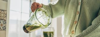Eine schenkt sich einen grünen Smoothie in ihr Glas.