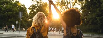 Zwei Mädchen halten Ihre Hände zu einem ausgetrecktem High five verbunden in die Abendsonne