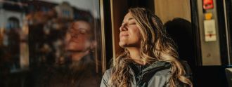 Eine Frau sitzt im Zug und schaut aus dem Fenster.