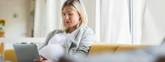 Schwangere Frau chattet am Tablet