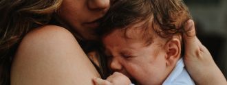 Eine junge Mutter hält traurig ihr Neugeborenes im Arm
