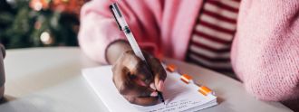 Eine Frau schreibt Neujahresvorsätze auf einen Block.