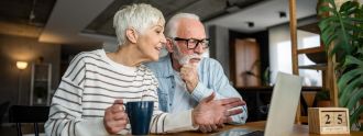 Ein älteres Paar sitzt vor dem Laptop und plant Termine.