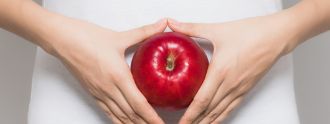 Frau haelt Apfel vor den Bauch