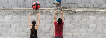 Eine Frau und ein Mann werfen Bälle gegen eine Wand.