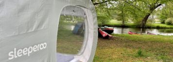 Ein Sleeperoo Würfelzelt steht an einem Fluss
