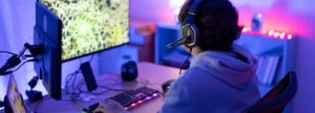 Ein Jugendlicher sitzt an seinem Schreibtisch und zockt am Computer.