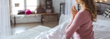 Eine Frau sitzt im Schneidersitz und meditiert.