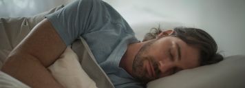 Ein Mann liegt im Bett und schläft.