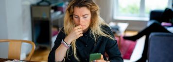 Eine Frau sitzt vor dem Laptop und schaut etwas verzweifelt.