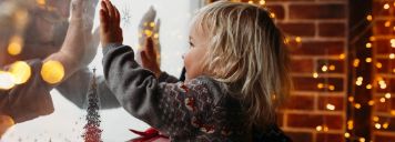 Ein kleiner Junge streckt seine Hände ans Fenster und auf der anderen Seite streckt sein Vater auch die Hände ans Fenster.