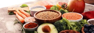 Verschiedene Lebensmittel mit gesunden Fetten, wie Lachs und Avocado, liegen auf einem Tisch.