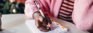 Eine Frau schreibt Neujahresvorsätze auf einen Block.