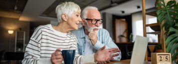 Ein älteres Paar sitzt vor dem Laptop und plant Termine.