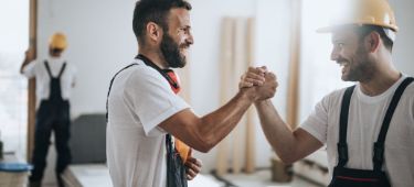 Handwerker auf einer Baustelle schlagen ein.