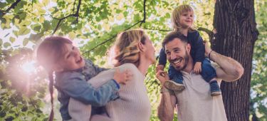 Eine Frau sitz mit einer Tasse in der Hand gemütlich auf ihrem Sofa.
