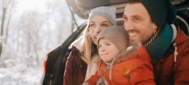 Eine Frau sitz mit einer Tasse in der Hand gemütlich auf ihrem Sofa.