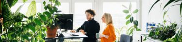Eine Frau und ein Mann arbeiten im Büro an einem Stehtisch.