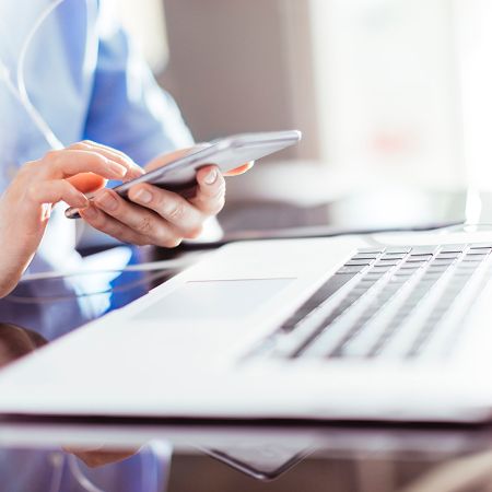 Eine Frau bedient am Arbeitsplatz ein Smartphone