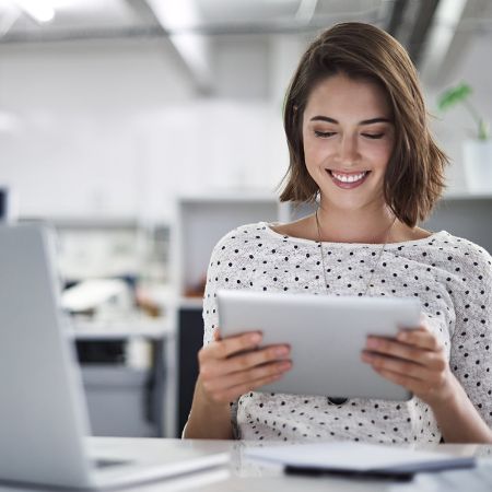 Frau schaut im Büro auf ihr Tablet.