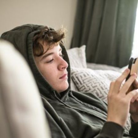 Junge auf dem Sofa vor dem Handy.