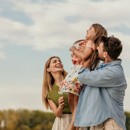 Eine Familie steht in der Natur und lacht.