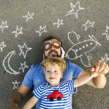Papa und Sohn liegen auf dem Boden und spielen Astronaut. 