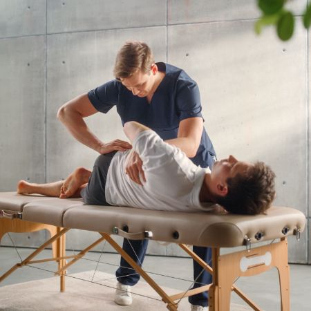 Ein Mann liegt auf einer Liege beim Osteopathen und wird behandelt.