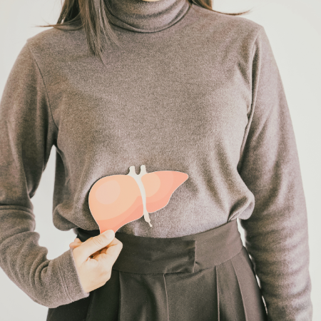Eine Frau hält eine Leber aus Pappe vor ihren Bauch.