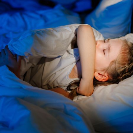 Das kleine Mädchen ist krank, liegt im Bett und hustet, es ist Nacht. 