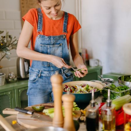 Eine junge Frau steht in der Küche und kocht eine gesunde Mahlzeit.