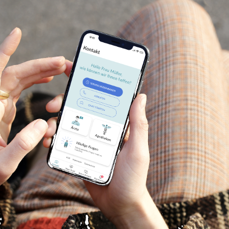 Eine Person sitzt auf einer Bank draußen und tippt mit dem Finger auf dem Smartphone in der Anwendung der Online-Sprechstunde.