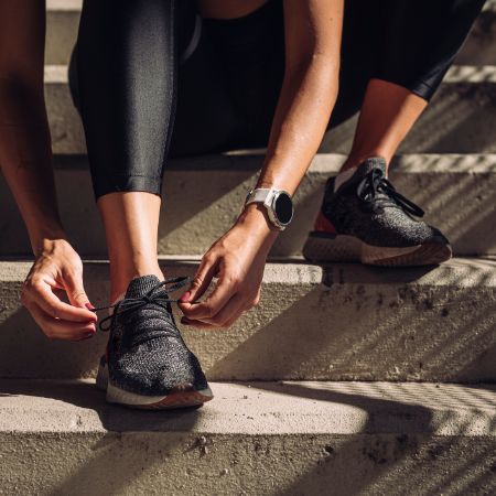 Sportlerin bindet Laufschuhe.