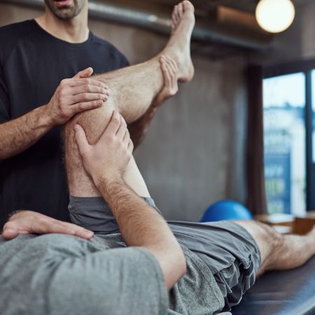 Sportler beim Phyio macht Übungen.