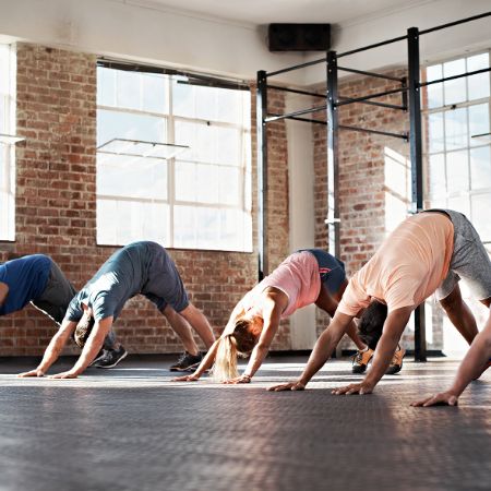 Yogagruppe macht Übungen, den herabschauenden Hund.