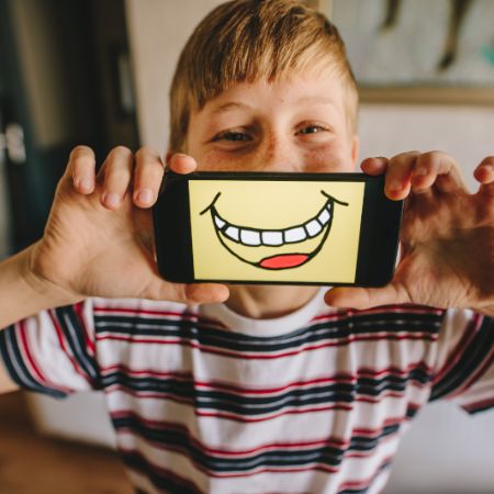 kind mit laecheln auf smartphone vor dem gesicht